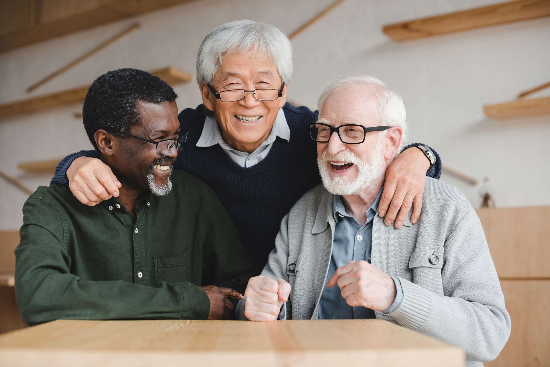 Three elderly men laughing together in a cozy room.