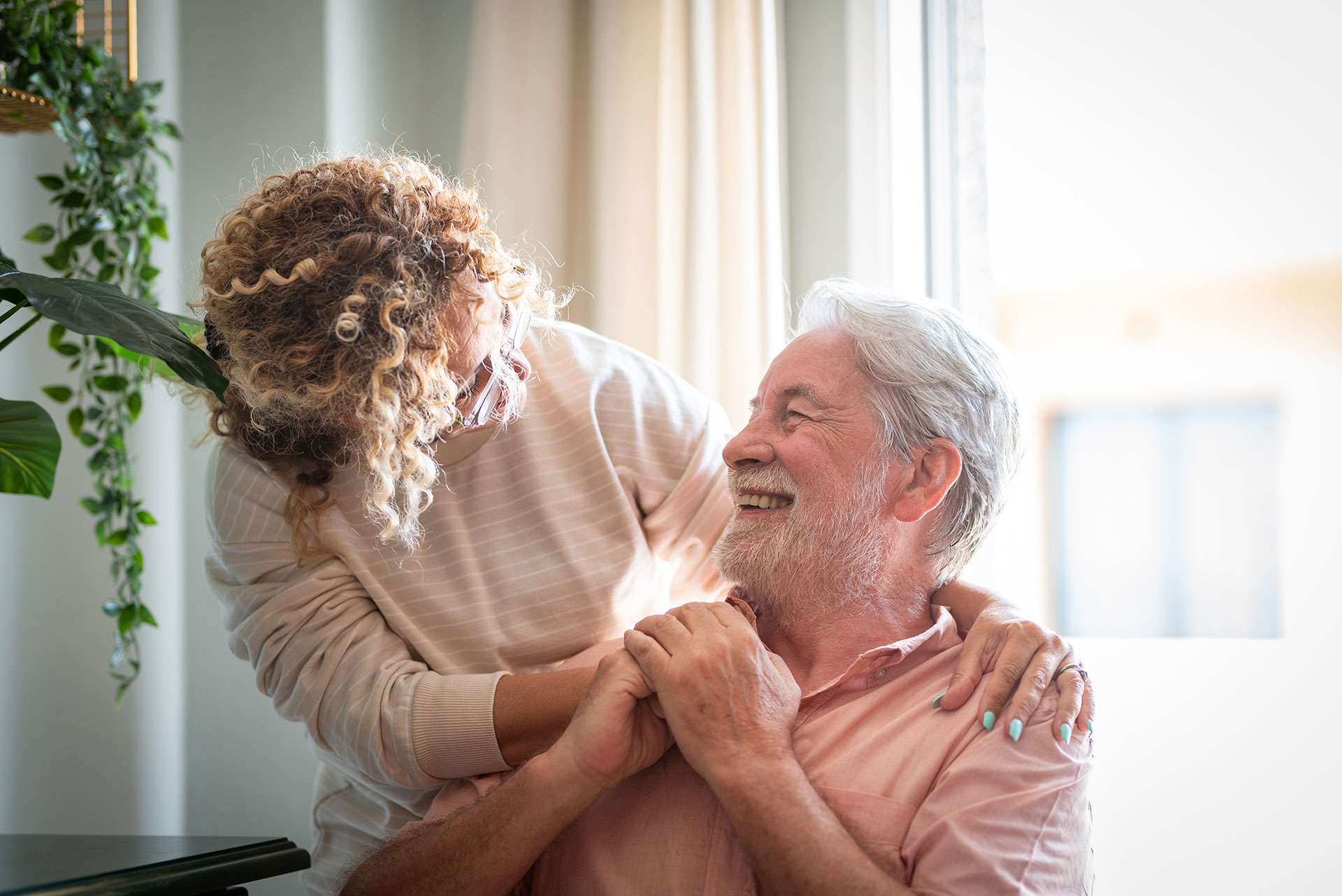 Smiling couple embracing near window, happy moment.